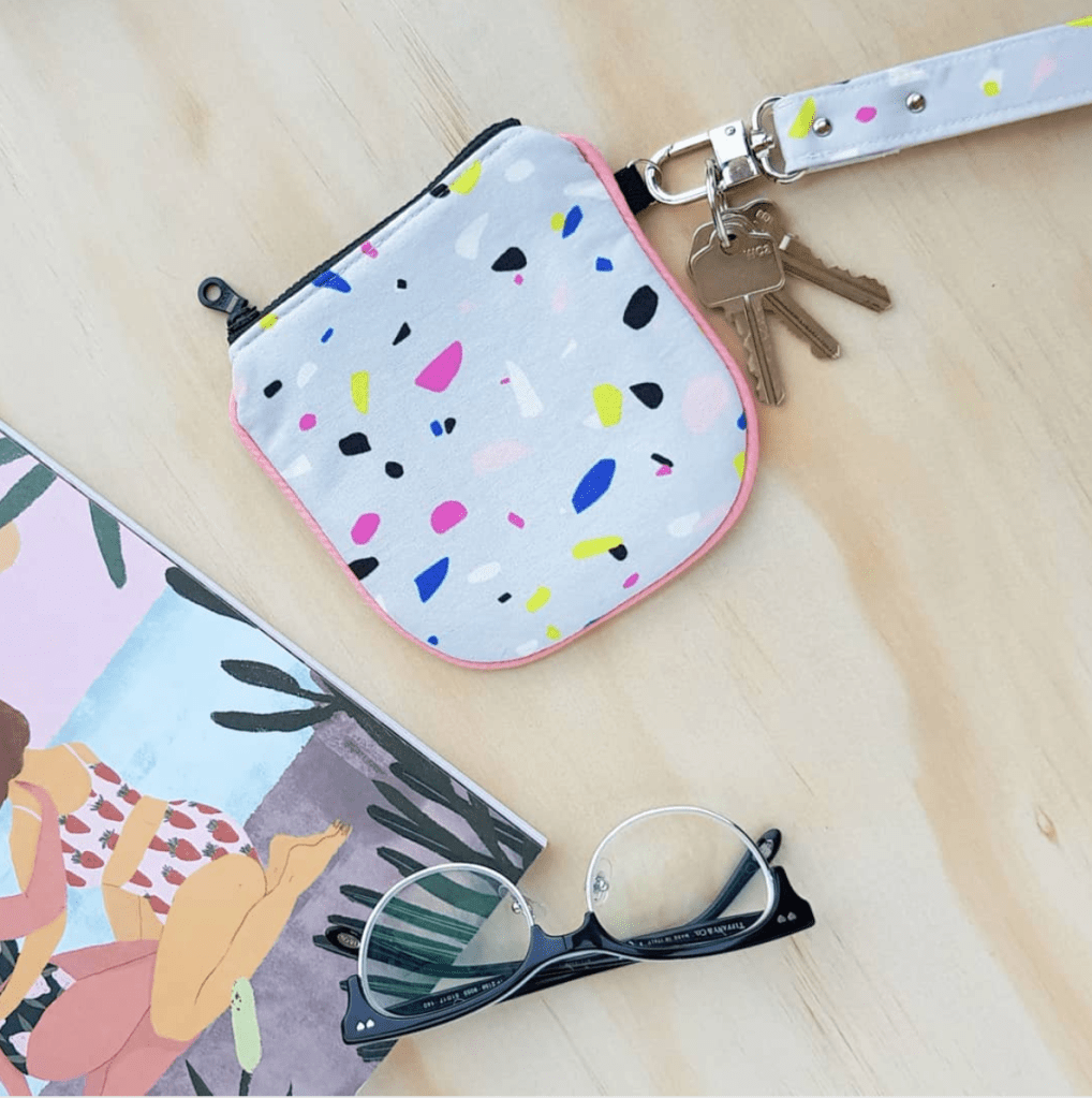 Photo of a mini wallet with a grey and multicoloured terrazzo patterned fabric. 